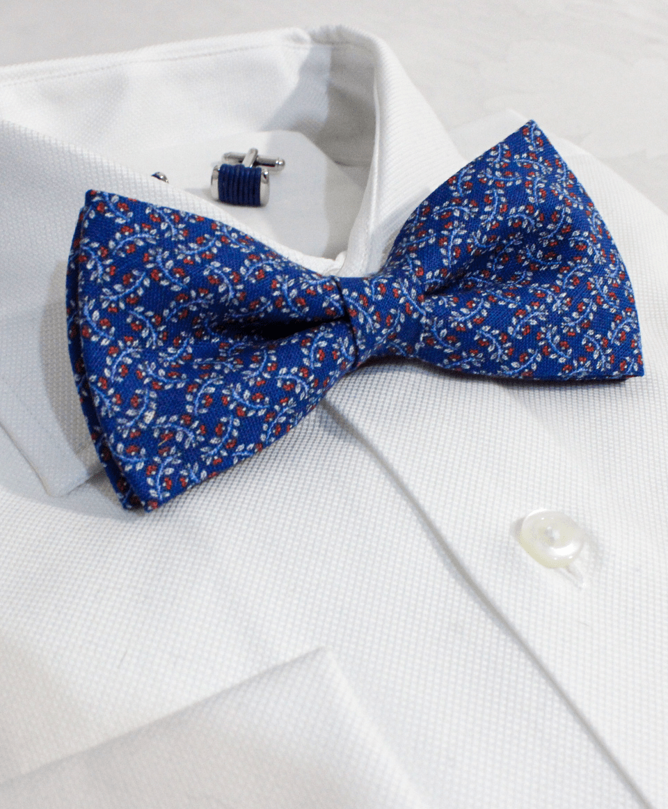 Pajarita azul de seda con estampado de flores sobre camisa blanca elegante, imagen para móviles