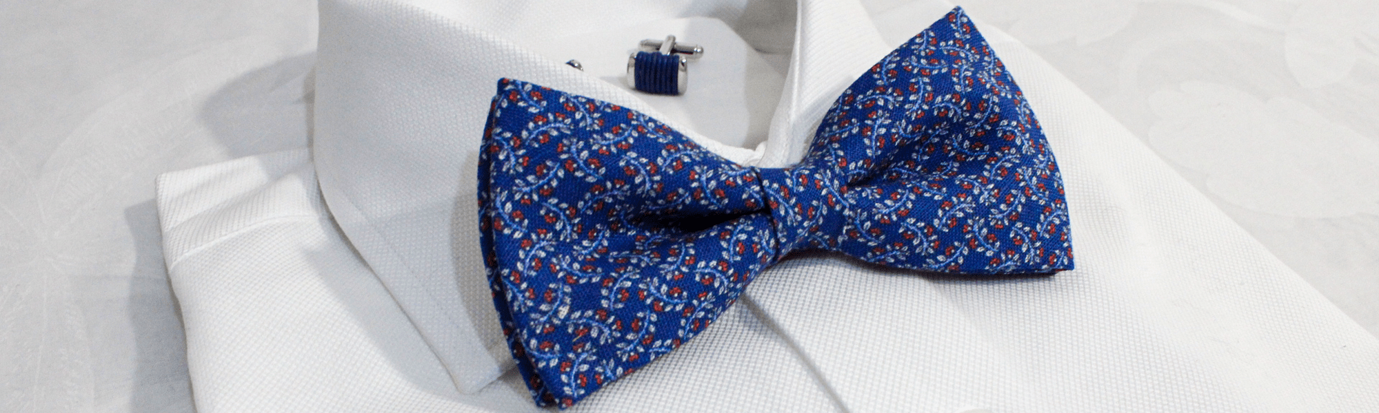 Pajarita azul de seda con estampado de flores sobre camisa blanca elegante