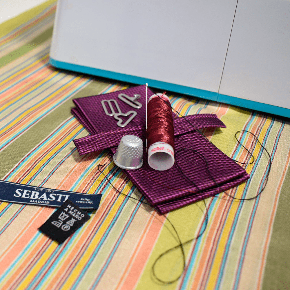 Pajarita en la fase de creación artesanal, junto a hilos y su etiqueta de Sebasti