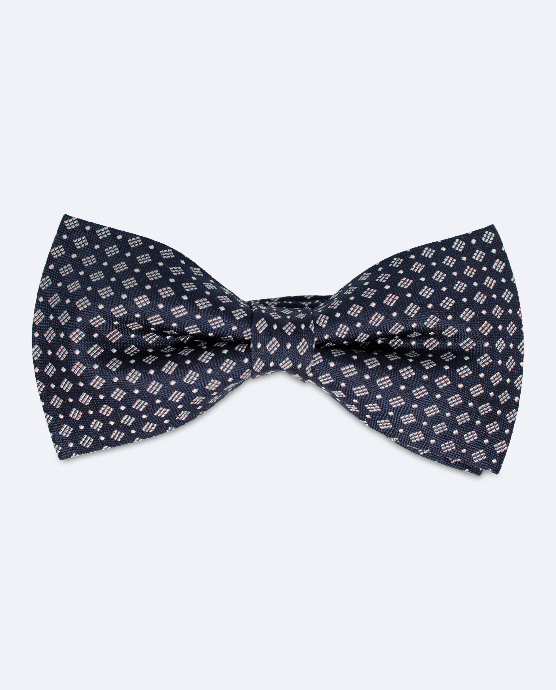 Pajarita azul marino, hecha a mano en 100% seda jacquard italiana, con diseño geométrico de rombos en diferentes formas de color blanco, vista frontal