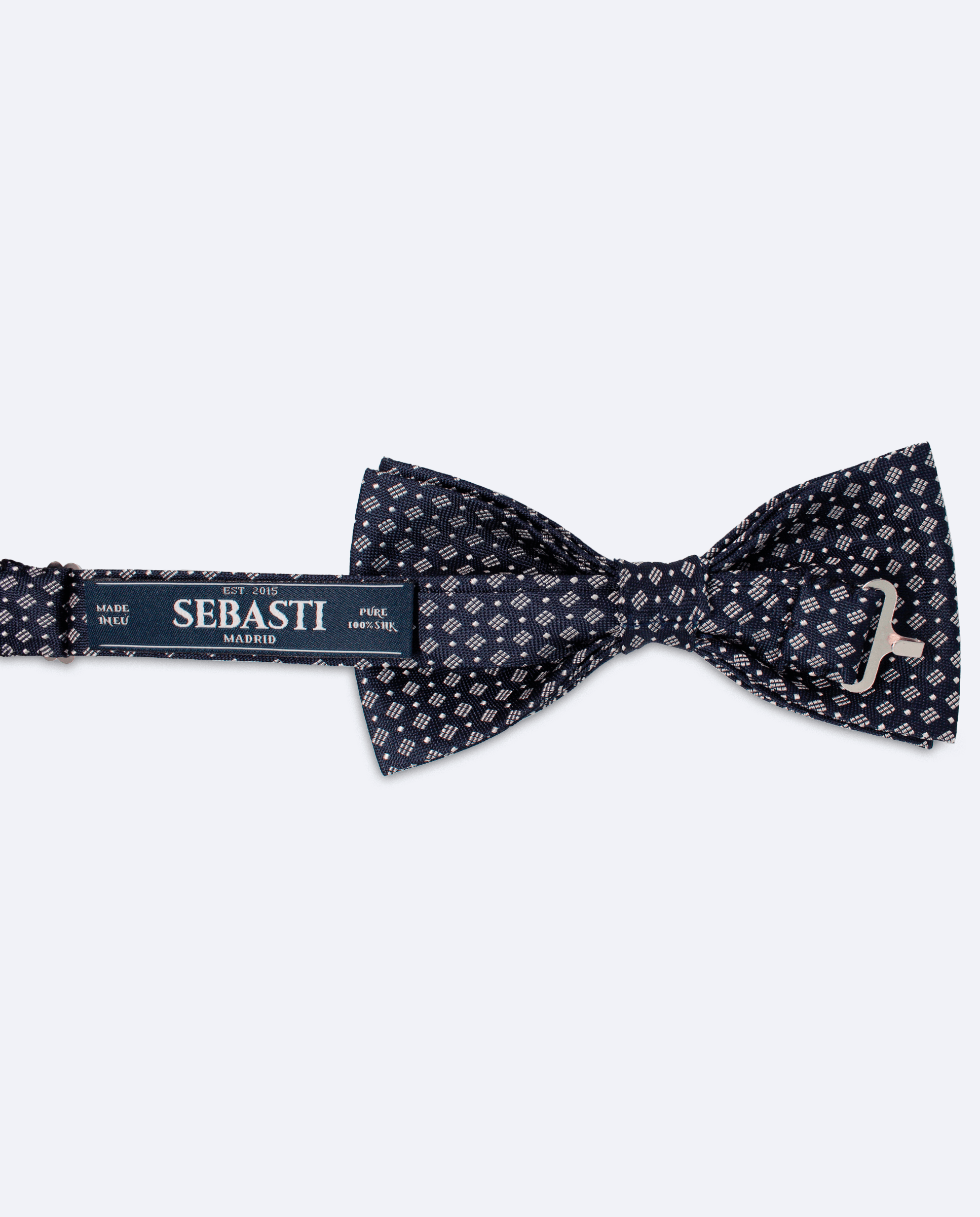 Vista trasera de la pajarita azul marino y blanca geométrica de seda. Incluye cinta ajustable y marca Sebasti en la etiqueta