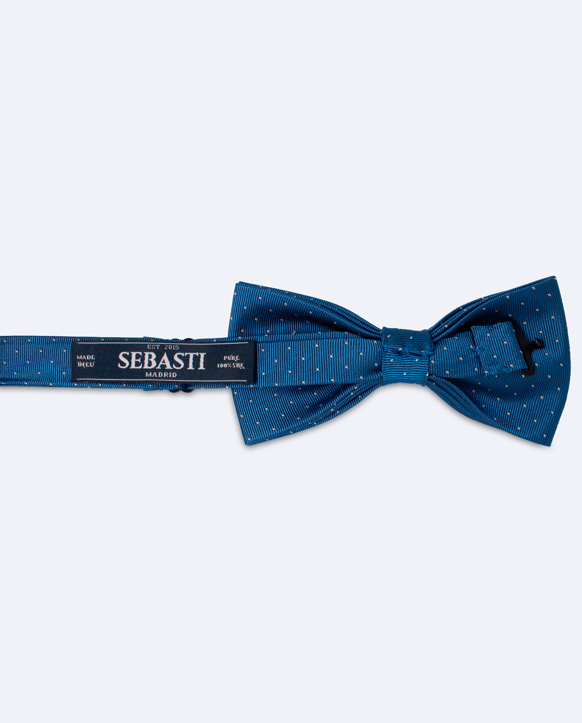 Vista trasera de la pajarita azul petróleo con lunares blancos de seda satén. Incluye cinta ajustable y marca Sebasti en la etiqueta
