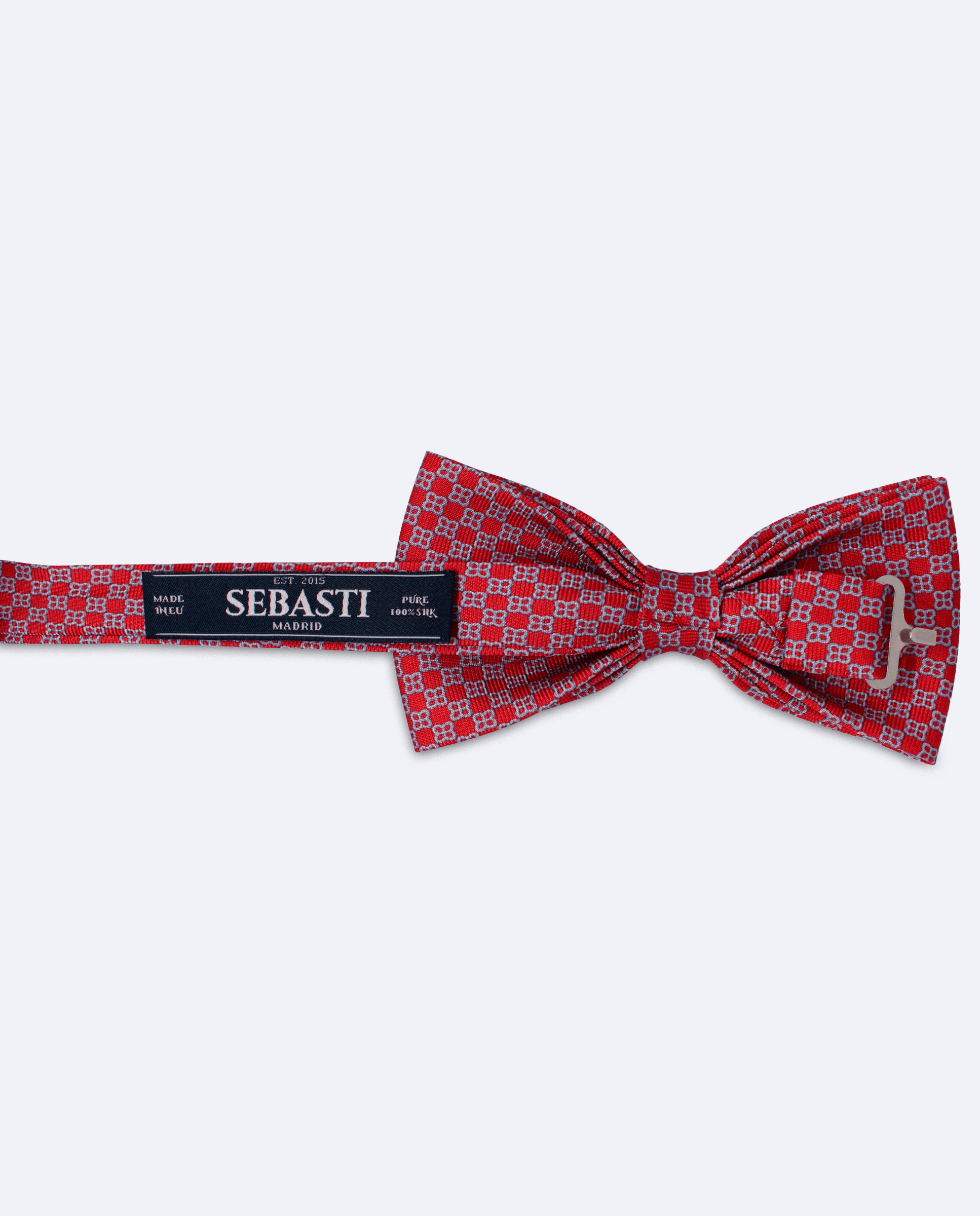 Vista trasera de la pajarita roja con diseño geométrico de flores azul claro en seda. Incluye cinta ajustable y marca Sebasti en la etiqueta