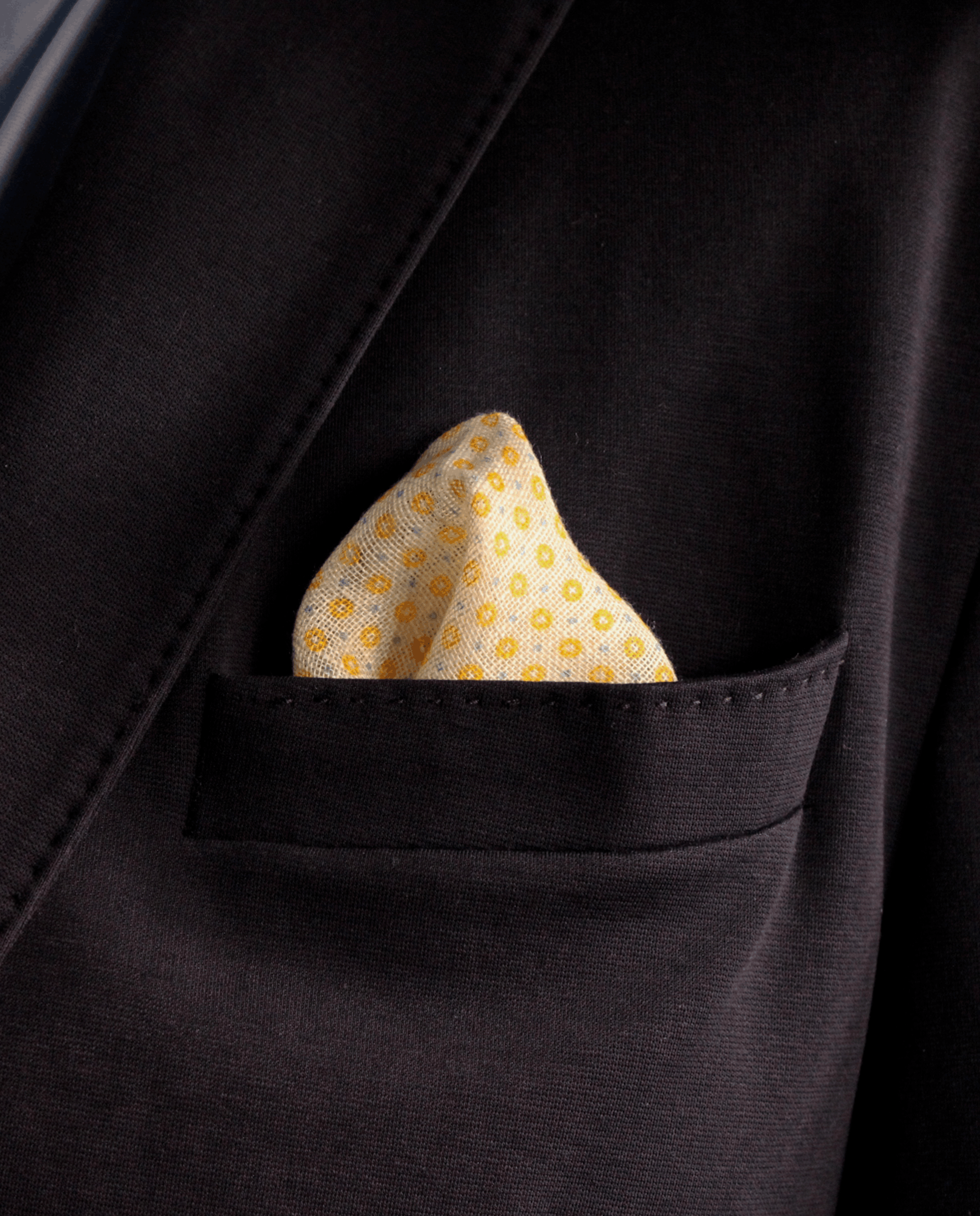 Pañuelo de bolsillo amarillo con círculos mostaza, colocado en el bolsillo de una americana | Sebasti