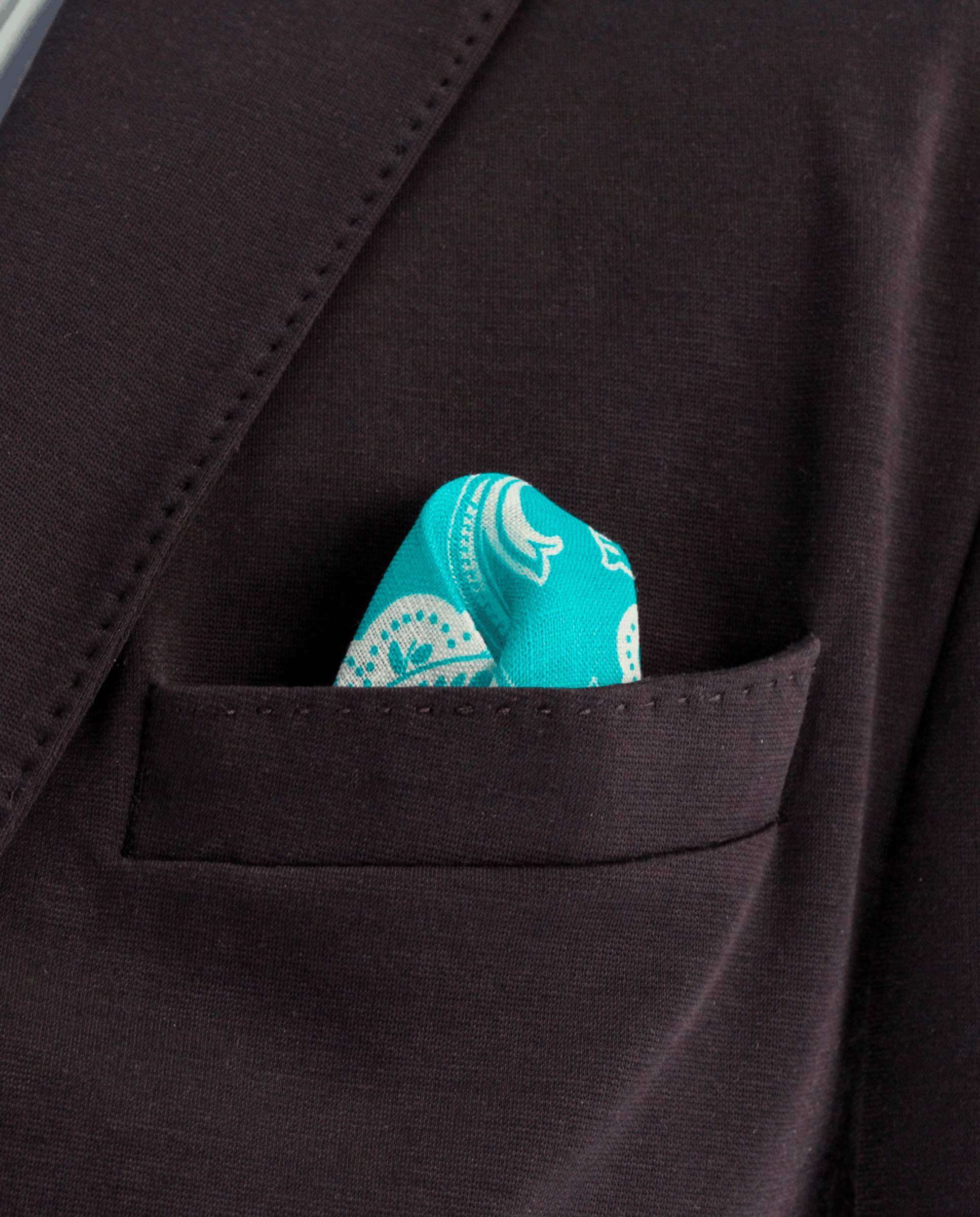 Pañuelo de bolsillo azul cian con cachemir blanco, colocado en el bolsillo de una americana | Sebasti