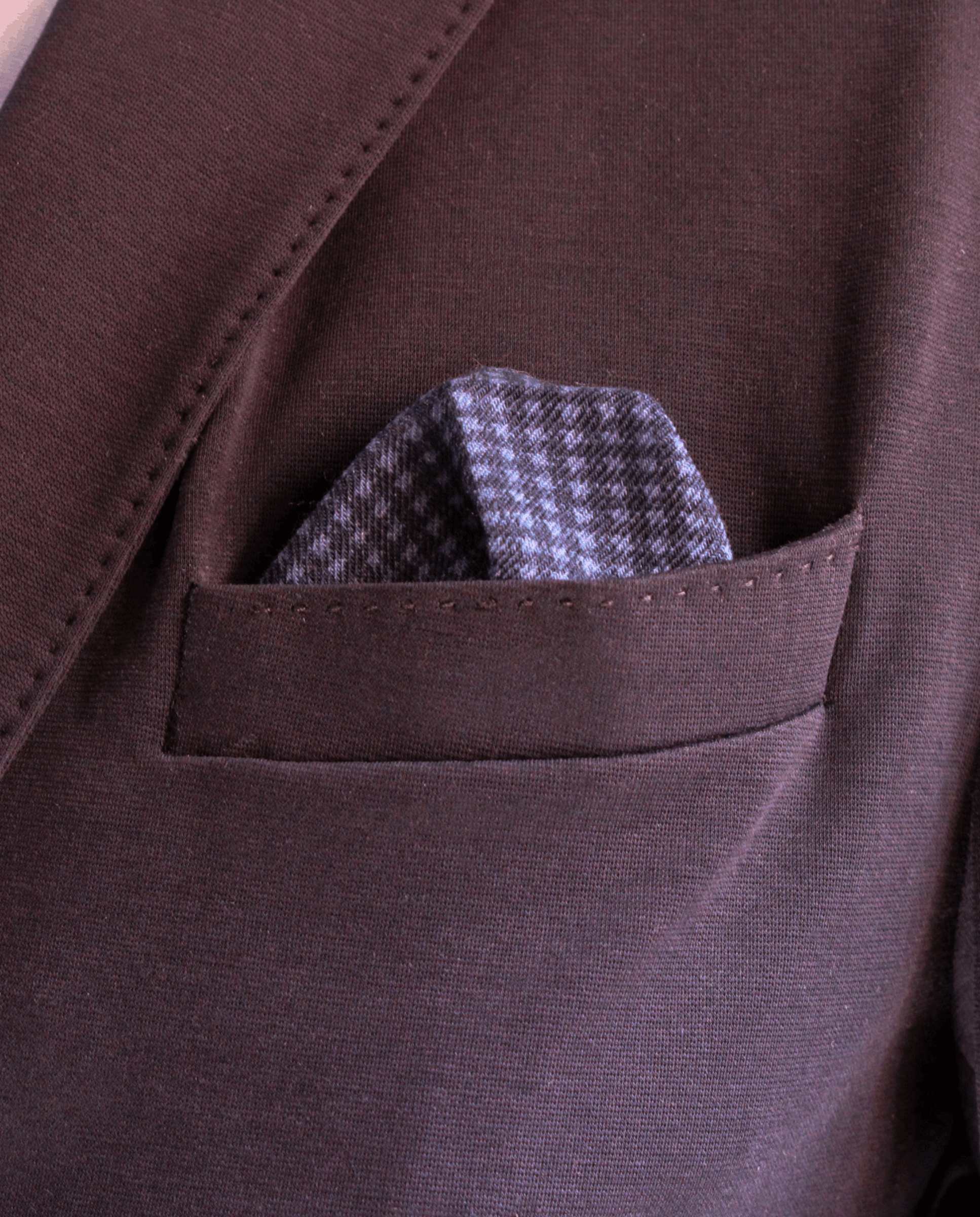 Pañuelo de bolsillo azul marino con cuadros y borde morado, colocado en el bolsillo de una americana | Sebasti