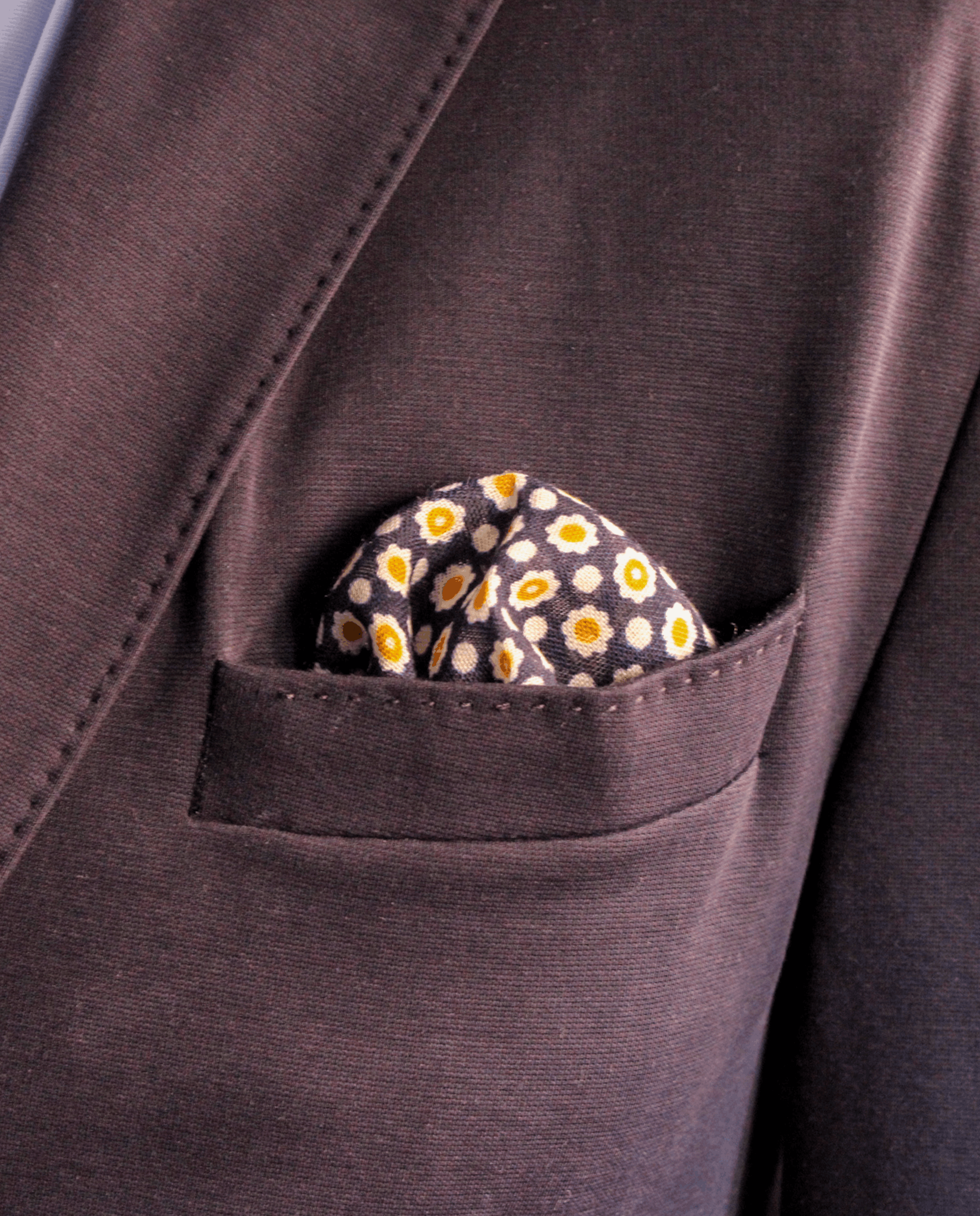 Pañuelo de bolsillo azul marino con flores doradas, colocado en el bolsillo de una americana