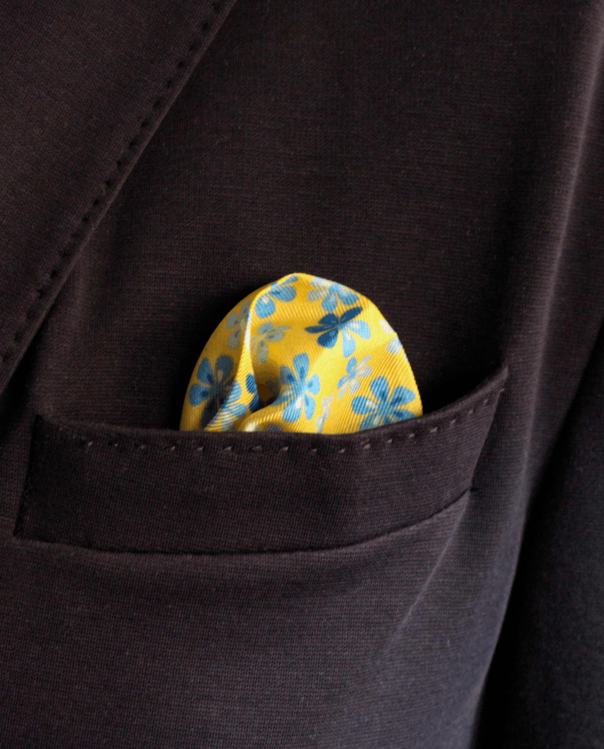 Pañuelo de bolsillo de seda amarillo con diseño de flores azules, colocado en el bolsillo de una americana | Sebasti
