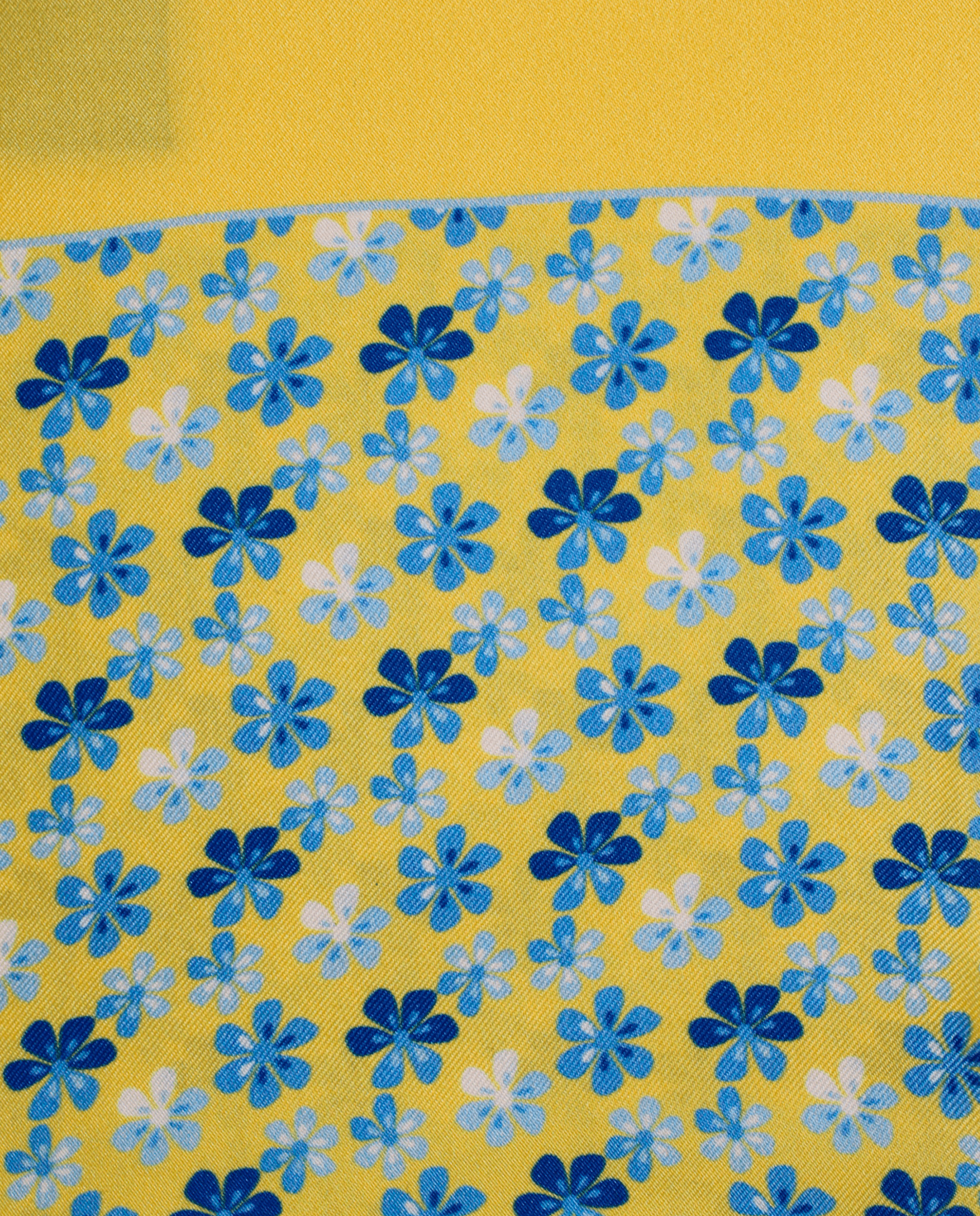 Pañuelo de bolsillo de seda amarillo con diseño de flores azules, detalle de cerca del tejido y el estampado