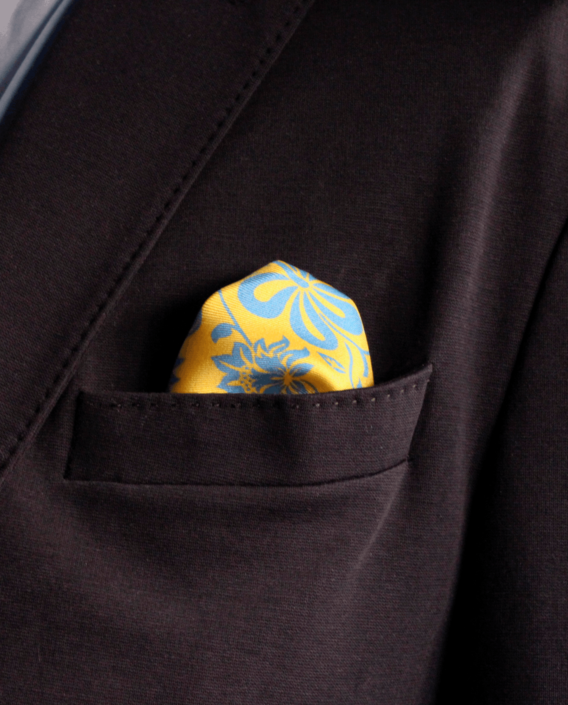 Pañuelo de bolsillo de seda amarillo con flores azules, colocado en el bolsillo de una americana | Sebasti