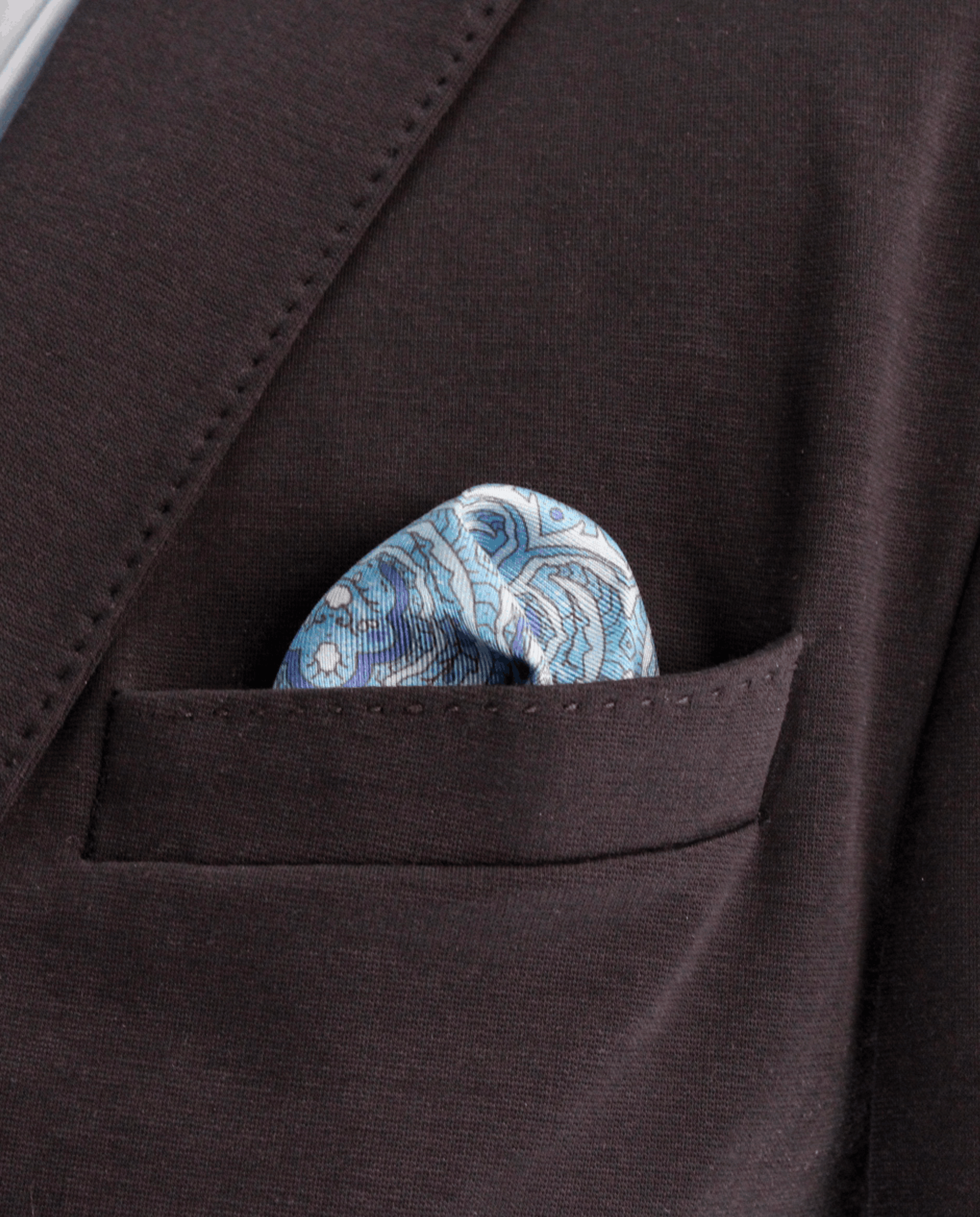 Pañuelo de bolsillo de seda azul eléctrico con cachemir azul claro, colocado en el bolsillo de una americana | Sebasti