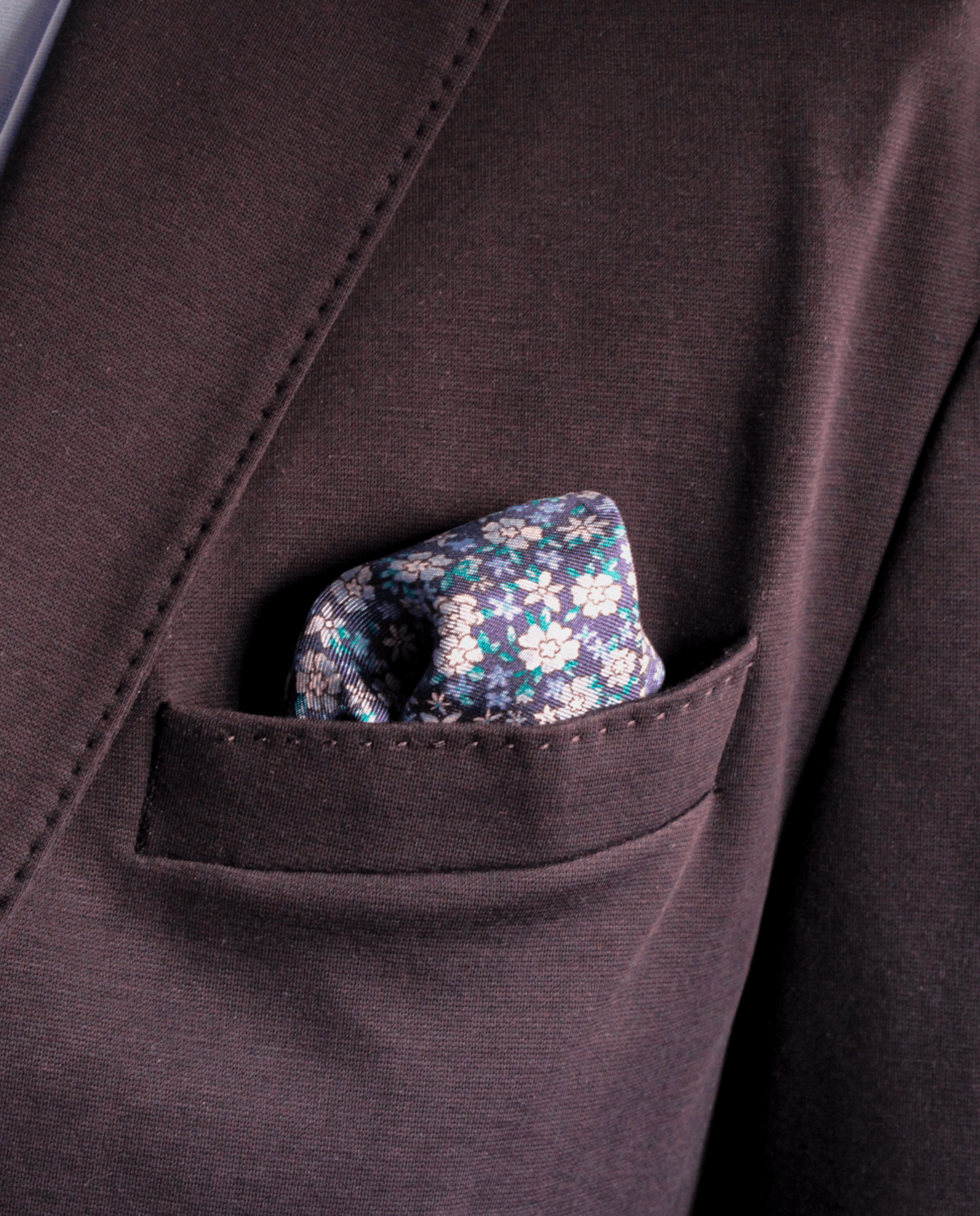 Pañuelo de bolsillo de seda azul marino con flores liberty azul claro, colocado en el bolsillo de una americana | Sebasti