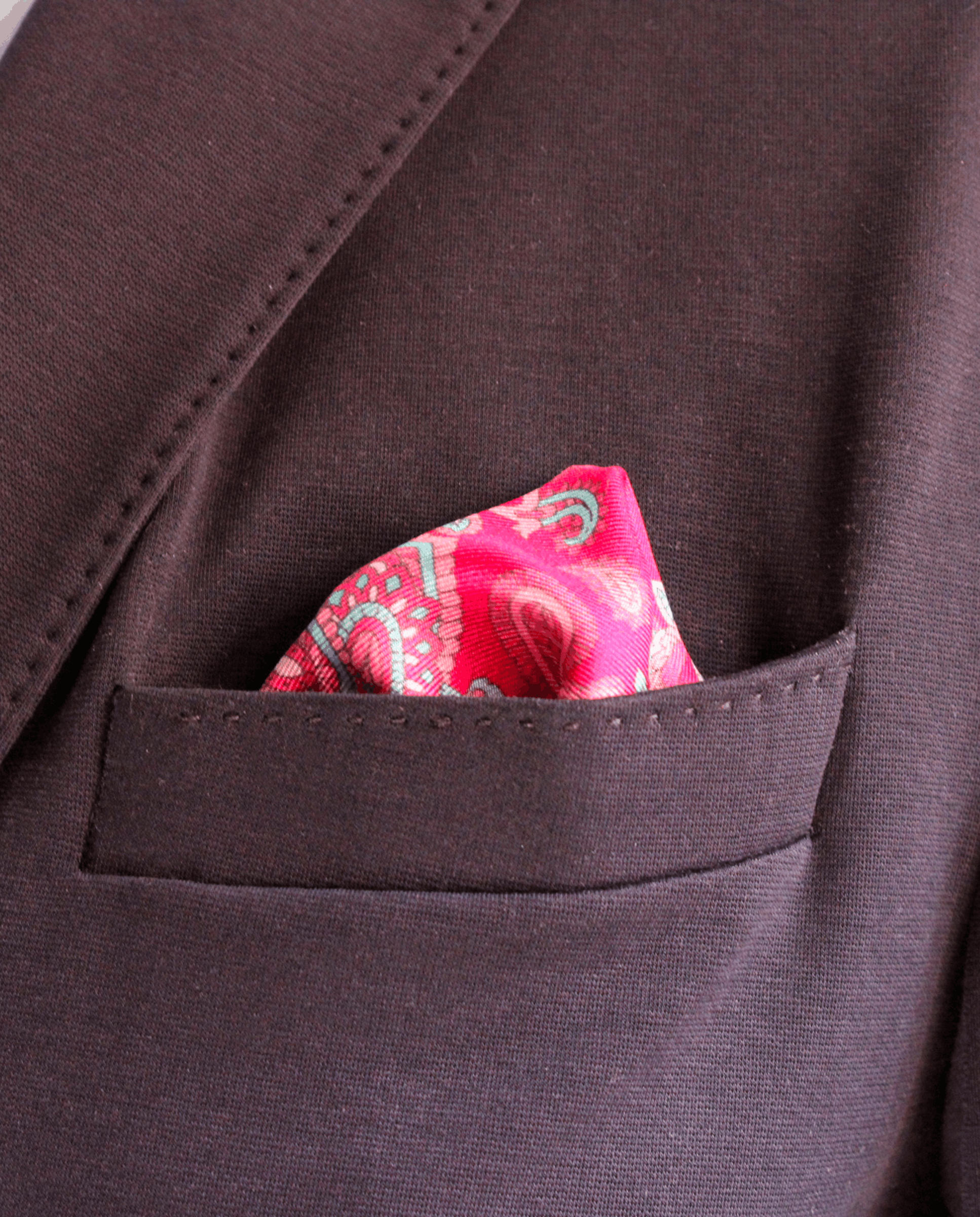 Pañuelo de bolsillo de seda fucsia con paisley azul cielo, colocado en el bolsillo de una americana | Sebasti