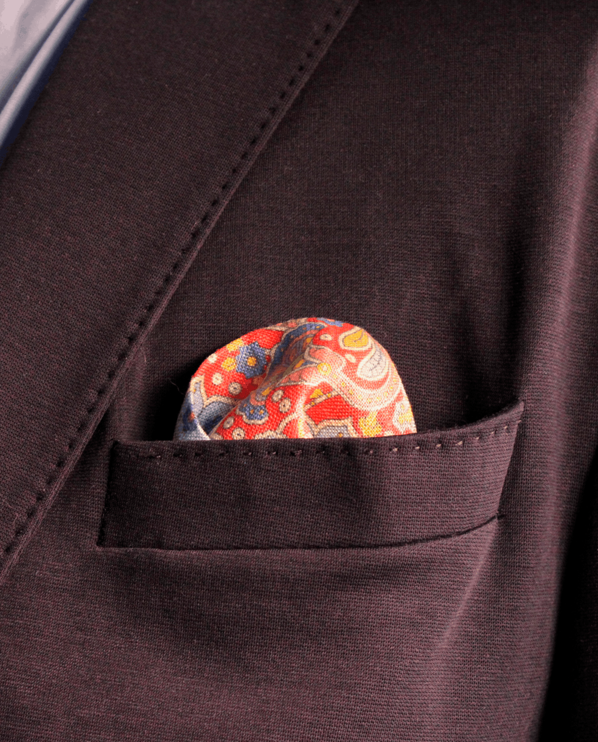 Pañuelo de bolsillo rojo con paisley multicolor, colocado en el bolsillo de una americana | Sebasti
