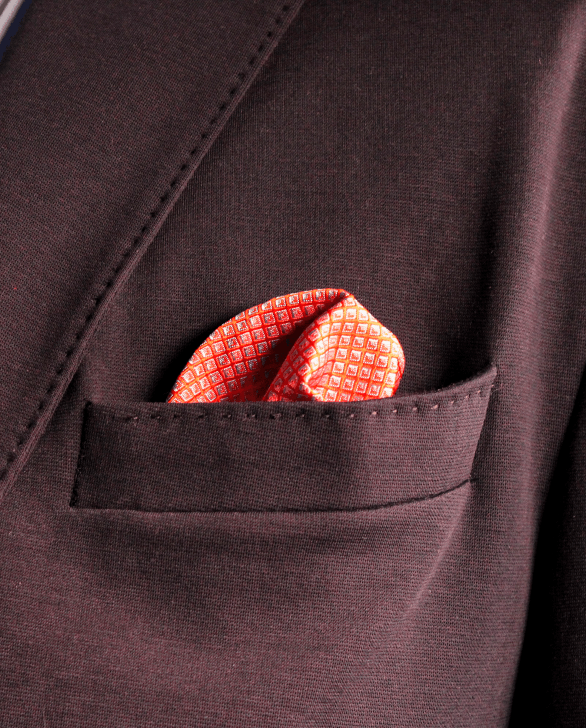 Pañuelo de bolsillo rosa intenso con rombos azul claro, colocado en el bolsillo de una americana | Sebasti